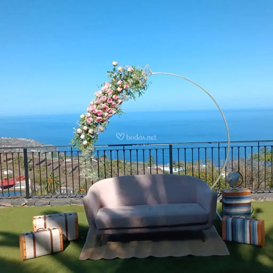 Zona chill-out con arco floral y vistas al mar
