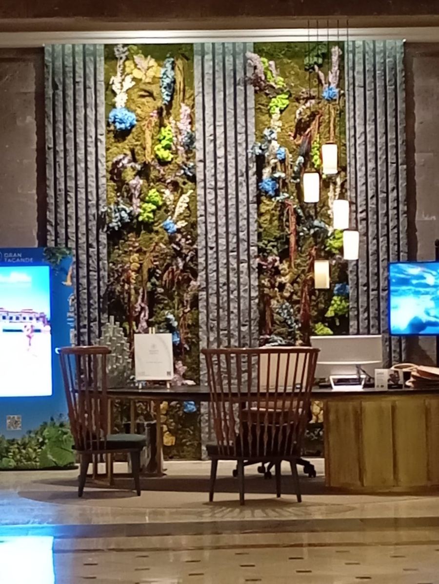 Recepción de hotel con pared vegetal preservada y flores